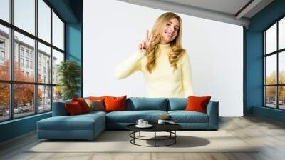 Young caucasian blonde woman joyful and carefree showing a peace symbol with fingers. Wall mural