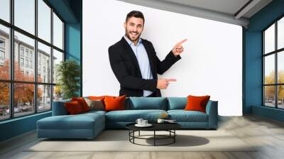 Young caucasian business man against a white background isolated excited pointing with forefingers away. Wall mural