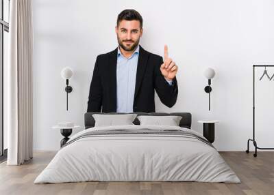 Young caucasian business man against a white background isolated showing number one with finger. Wall mural