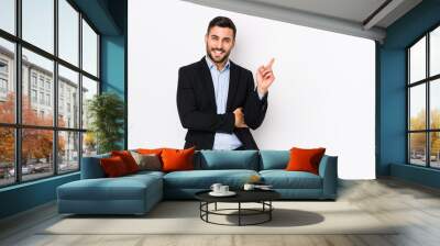 Young caucasian business man against a white background isolated smiling cheerfully pointing with forefinger away. Wall mural