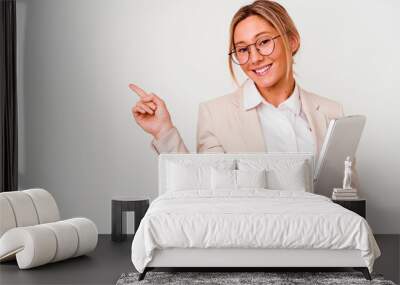 Young caucasian business woman holding a laptop isolated on white background smiling and pointing aside, showing something at blank space. Wall mural