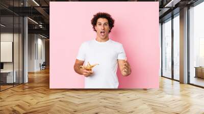 Young caucasian curly man  holding a magic lamp celebrating a victory or success Wall mural