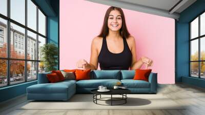 Young caucasian fitness woman doing sport isolated points down with fingers, positive feeling. Wall mural