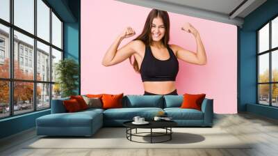 Young caucasian fitness woman doing sport isolated showing strength gesture with arms, symbol of feminine power Wall mural