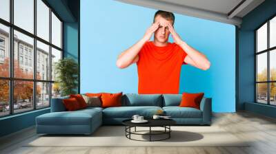 Young caucasian handsome man having a head ache, touching front of the face. Wall mural