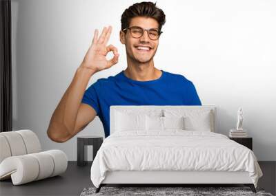 Young caucasian handsome man isolated cheerful and confident showing ok gesture. Wall mural