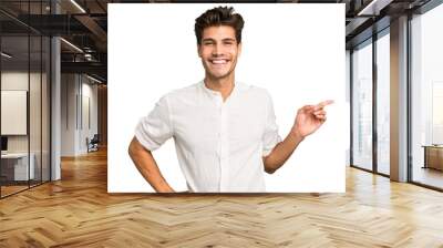 Young caucasian handsome man isolated smiling cheerfully pointing with forefinger away. Wall mural