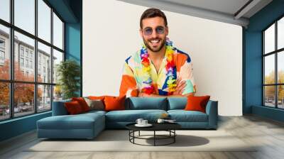 Young caucasian man dancing on a hawaiian party isolated on white background laughing and having fun. Wall mural