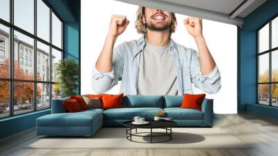 Young Caucasian man in studio setting celebrating a victory, passion and enthusiasm, happy expression. Wall mural