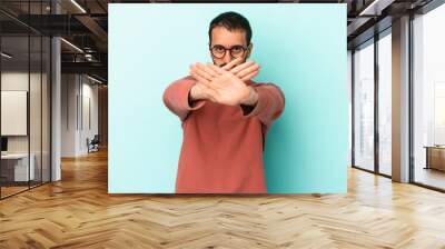 Young caucasian man isolated on blue background doing a denial gesture Wall mural