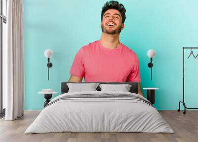 Young caucasian man isolated on blue background relaxed and happy laughing, neck stretched showing teeth. Wall mural