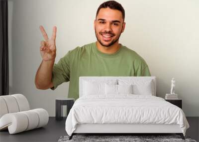 Young caucasian man isolated on white background joyful and carefree showing a peace symbol with fingers. Wall mural