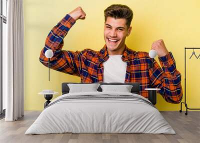 Young caucasian man isolated on yellow background cheering carefree and excited. Victory concept. Wall mural