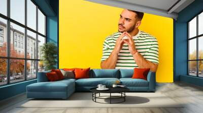 Young caucasian man isolated on yellow background making up plan in mind, setting up an idea. Wall mural