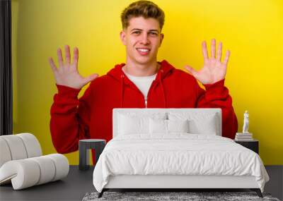 Young caucasian man isolated on yellow background showing number ten with hands. Wall mural