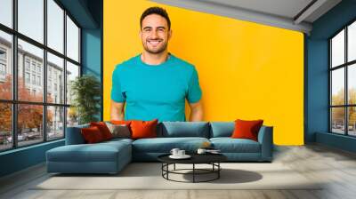 Young caucasian man isolated on yellow bakground laughs and closes eyes, feels relaxed and happy. Wall mural