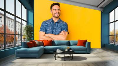 Young caucasian man isolated on yellow bakground smiling confident with crossed arms. Wall mural