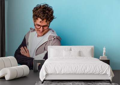 Young caucasian man wearing eyeglasses isolated on blue background smiling confident with crossed arms. Wall mural