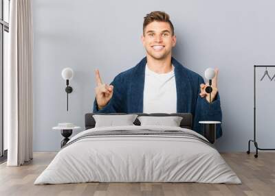 Young caucasian man wearing pajama indicates with both fore fingers up showing a blank space. Wall mural