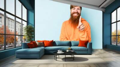 Young caucasian red-haired man isolated on blue background showing number one with finger. Wall mural