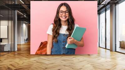 Young caucasian student woman isolated on pink background laughing and having fun. Wall mural