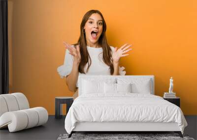 Young caucasian woman celebrating a victory or success, he is surprised and shocked. Wall mural