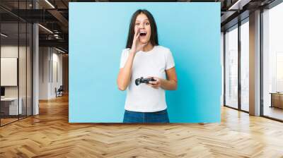 Young caucasian woman holding a game controller shouting excited to front. Wall mural