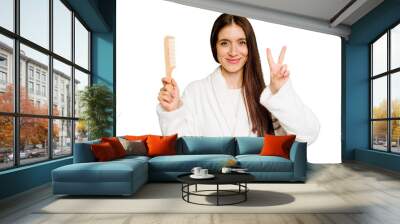 Young caucasian woman holding an hair comb isolated showing number two with fingers. Wall mural