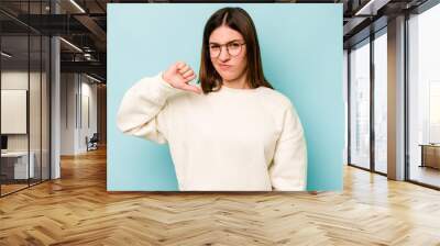 Young caucasian woman isolated on blue background showing thumb down, disappointment concept. Wall mural