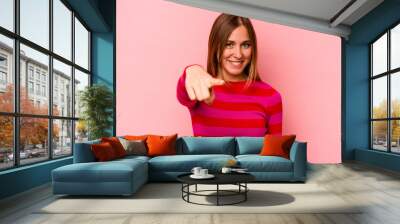 Young caucasian woman isolated on pink background cheerful smiles pointing to front. Wall mural