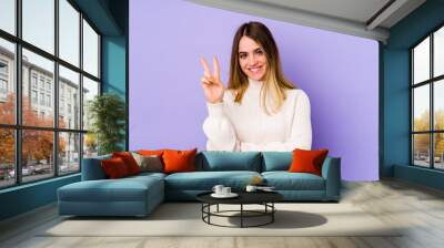 Young caucasian woman isolated on purple background showing number two with fingers. Wall mural