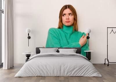 Young caucasian woman isolated on white background points sideways, is trying to choose between two options. Wall mural