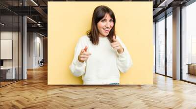 Young caucasian woman isolated on yellow background pointing to front with fingers. Wall mural