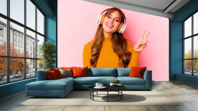 Young caucasian woman listening music with headphones isolated showing number two with fingers. Wall mural