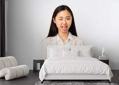 Young chinese business woman isolated funny and friendly sticking out tongue. Wall mural