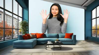 Young chinese woman isolated on a blue background showing number ten with hands. Wall mural