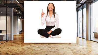 Young colombian woman sitting on the floor isolated showing number one with finger. Wall mural