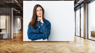 Young cute woman looking sideways with doubtful and skeptical expression. Wall mural