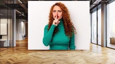 Young ginger caucasian woman isolated on white background keeping a secret or asking for silence. Wall mural