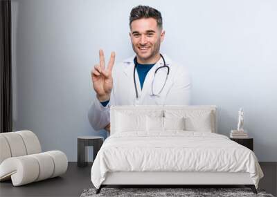 Young handsome doctor man showing number two with fingers. Wall mural