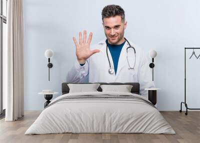 young handsome doctor man smiling cheerful showing number five with fingers. Wall mural