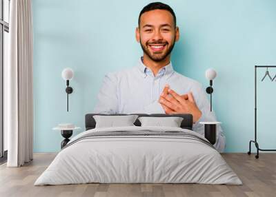 Young hispanic man isolated on blue background has friendly expression, pressing palm to chest. Love concept. Wall mural