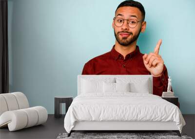 Young hispanic man isolated on blue background showing number one with finger. Wall mural