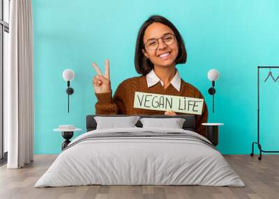 Young hispanic mixed race woman holding a vegan life placard showing number two with fingers. Wall mural