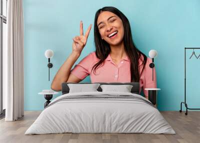 Young hispanic woman isolated on blue background showing number two with fingers. Wall mural