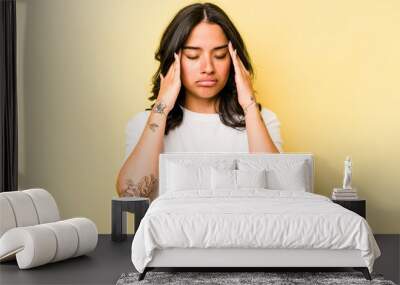 Young hispanic woman isolated on yellow background having a head ache, touching front of the face. Wall mural