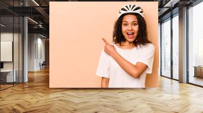 Young hispanic woman wearing a helmet bike isolated on blue background pointing to the side Wall mural