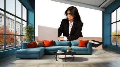 Young indian woman in a table with a laptop and tablet using a mobile phone isolated Wall mural