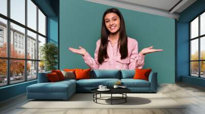 Young Indian woman isolated on blue background makes scale with arms, feels happy and confident. Wall mural