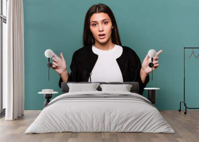 Young Indian woman isolated on blue background pointing to different copy spaces, choosing one of them, showing with finger. Wall mural